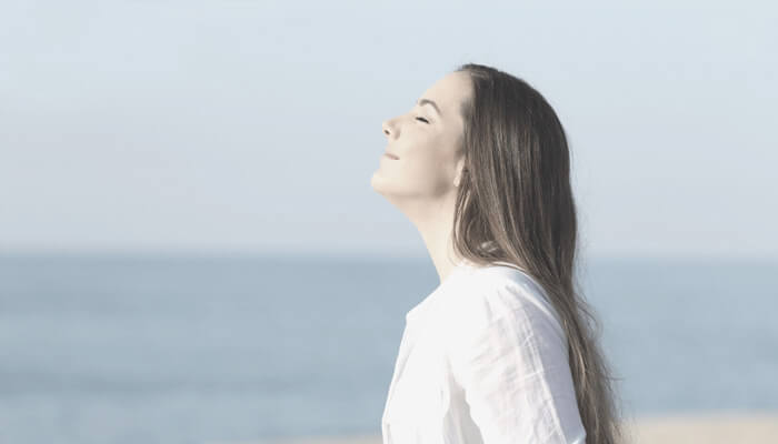 Woman inhaling deeply facing the sun
