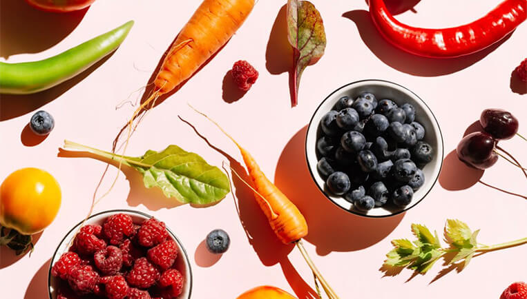 berries and veggies laid out on a pink background